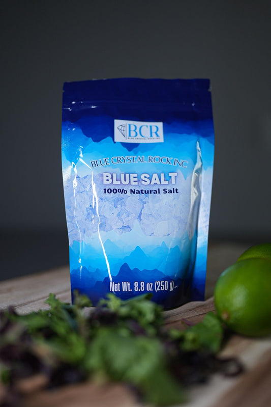 Bag of BCR Blue Salt on a wooden surface with greenery